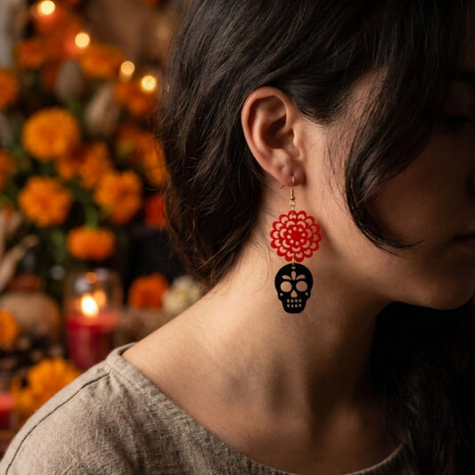 Modelo utilizando aretes de acrilico cortados a laser en forma de calavera negra y cempasuchil naranja