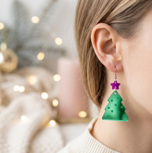 Modelo utilizando aretes de corte laser en forma de arbol navideño en acrilico espejo verde y fiuscha
