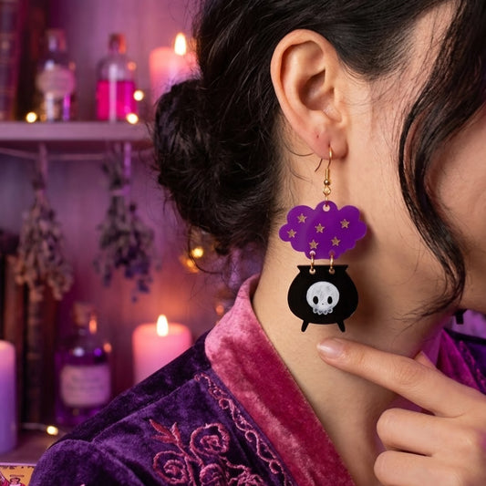 Aretes cortados a laser en forma de caldero en acrilico negri grabado y nube morada usados por modelo en fondo magico