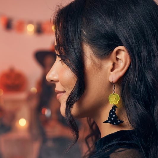 Modelo usando aretes cortados a laser en forma de sombrero de bruja en acrilico negro y acrilico amarillo una calavera