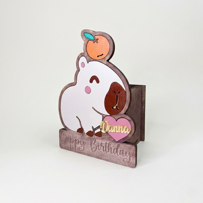 Cajas dulceras personalizadas con forma de capibara y una naranja en la cabeza hechas de madera MDF cortada a láser. Ideal como recuerdos de cumpleaños, centros de mesa infantiles y organizador de escritorio reutilizable.